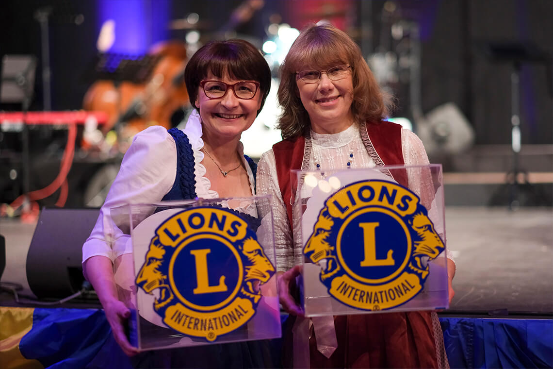 Länderball 2026 - Zwei Frauen halten Lions‑Club‑Logos auf der Bühne des Steintor‑Varietés Halle